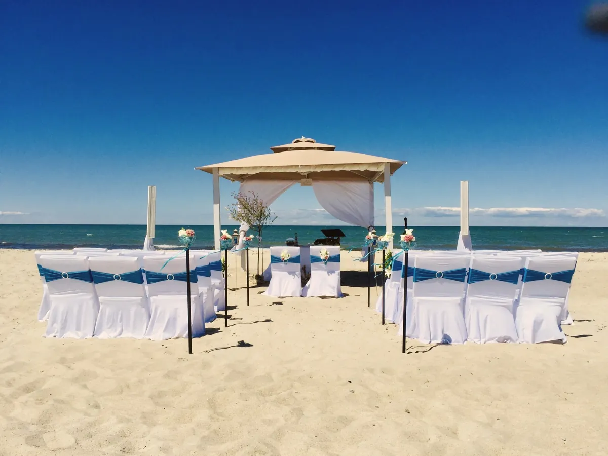 Holzpavillon mit Stuhlreihen und blauen Schleifen am Ostseestrand