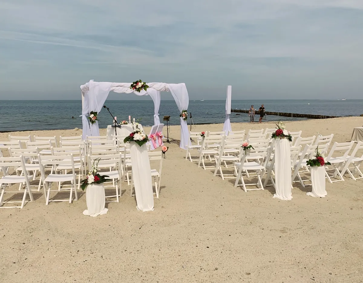 Weißer Traubogen und Stuhlreihen am weiten Ostseestrand