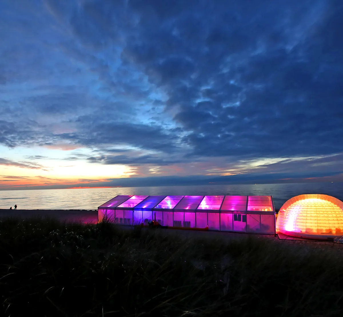 Festlich beleuchtetes Zelt und Lounge am Ostseestrand in der Dämmerung