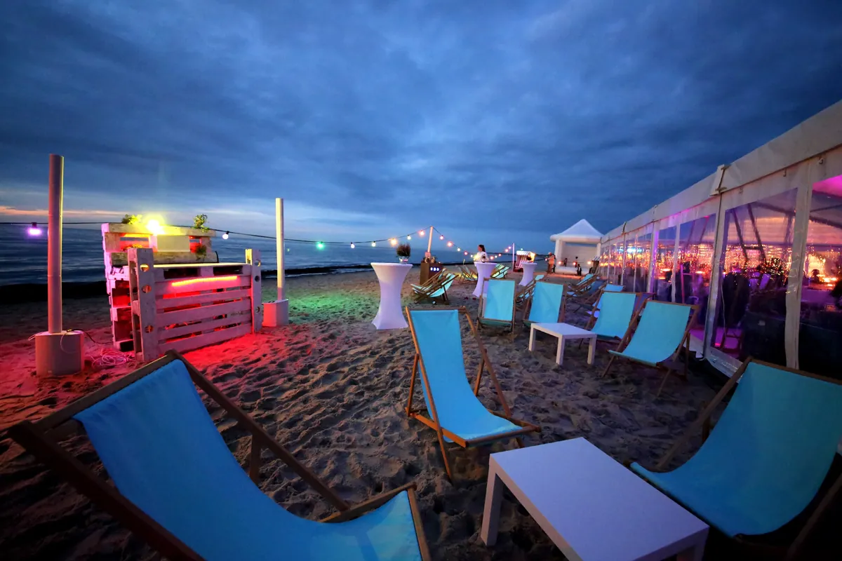 Strandlounge mit Liegen und Schirmen vor dem Festzelt